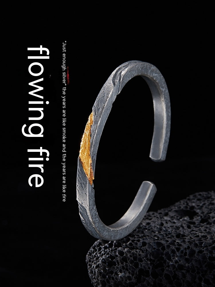 Silver bracelet with gold accent on a black background, featuring the text 'flowing fire'.