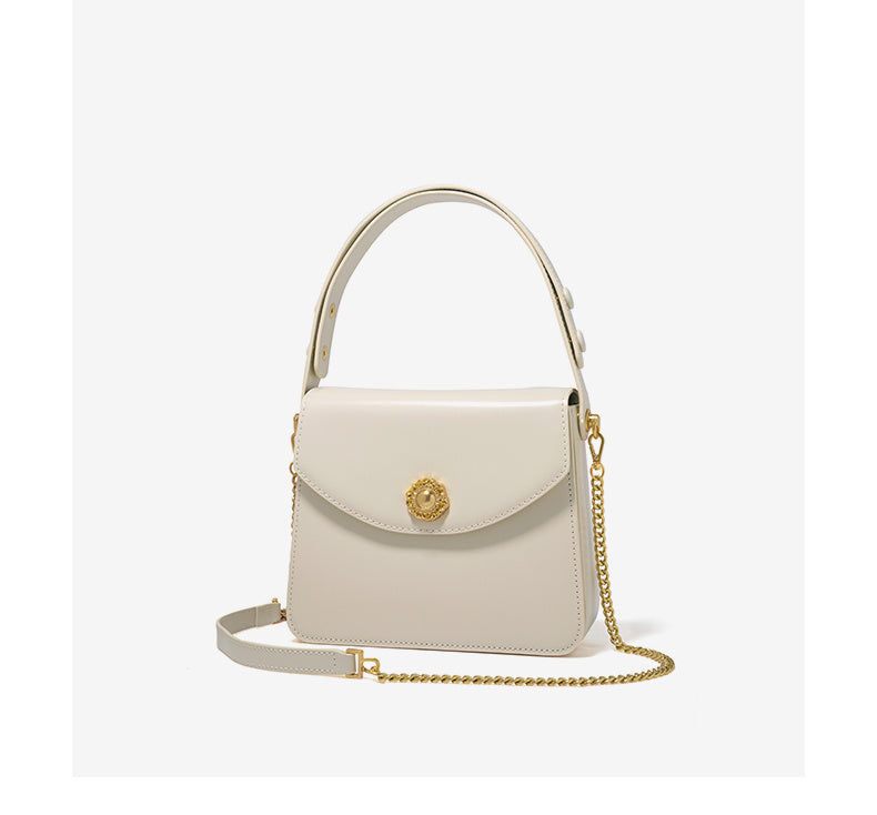 White handbag with gold chain and emblem on a white background
