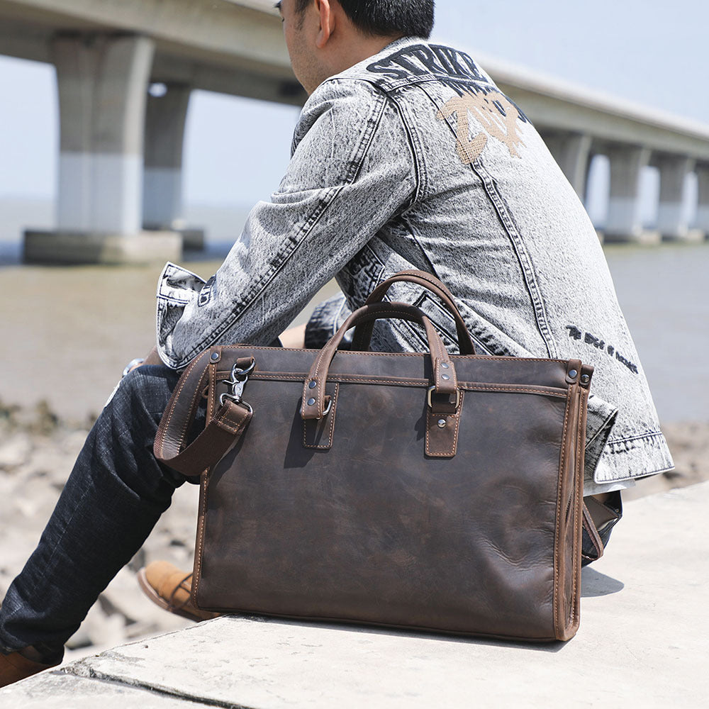 Person sitting outdoors with a brown leather briefcase
