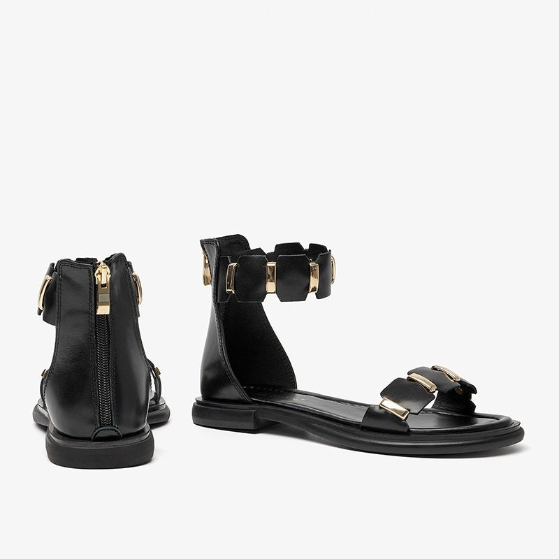 Black sandals with gold buckles on a white background