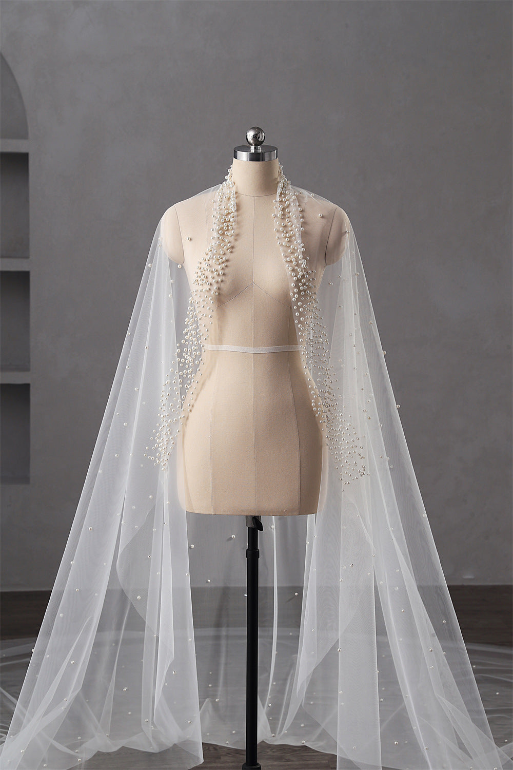White bridal veil with lace details on a mannequin against a gray background