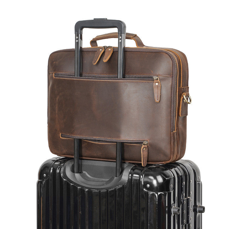 Brown leather briefcase on top of a black suitcase with a white background