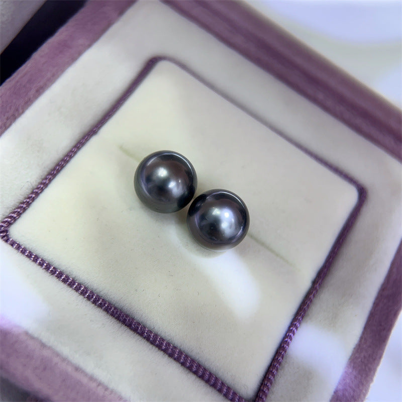 Two black pearls in a jewelry box with a purple interior.