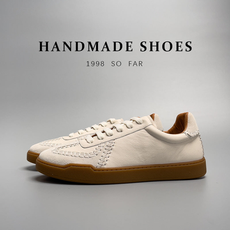 Pair of white sneakers with brown soles on a gray background, labeled 'Handmade Shoes'.