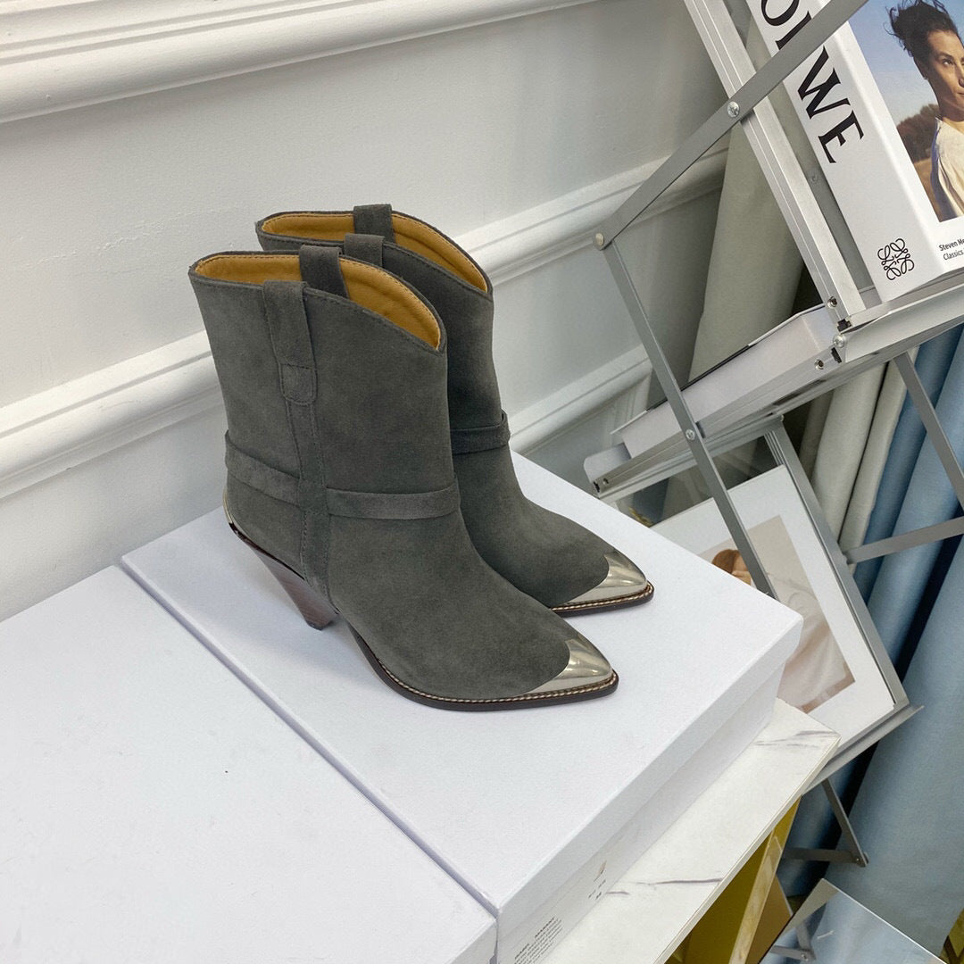 Pair of gray suede boots on a white surface with a magazine in the background.