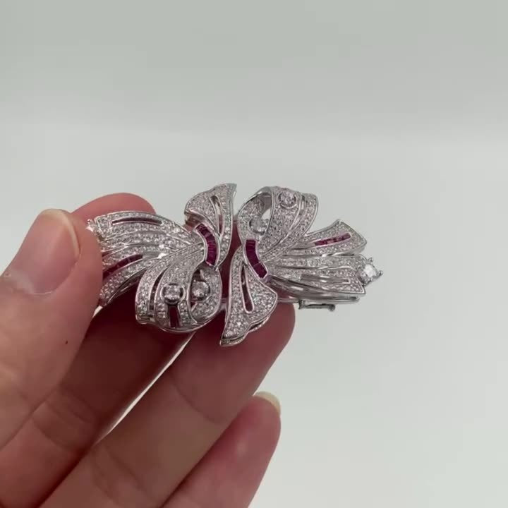 Silver butterfly-shaped earring held by a hand on a white background