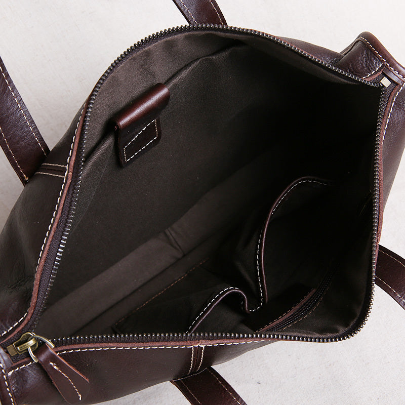Brown leather bag with open front pocket on a light gray background