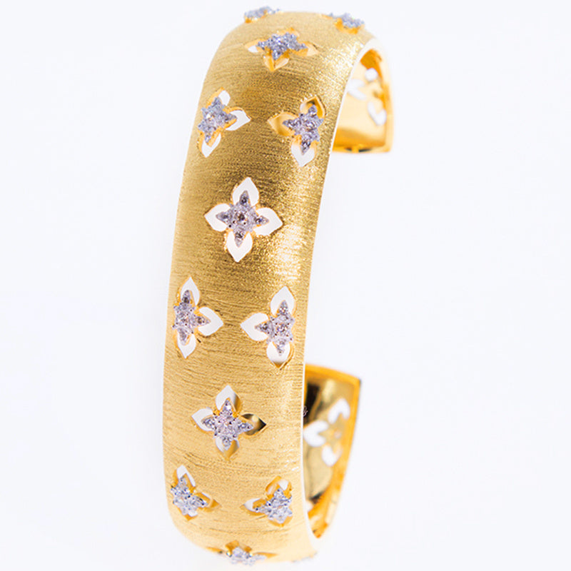 Gold bracelet with star-shaped diamond embellishments on a white background