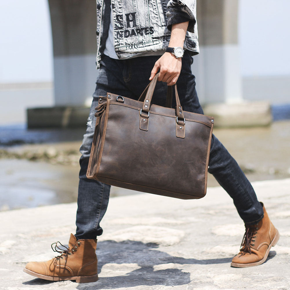 Person holding a brown leather briefcase with a blurred background