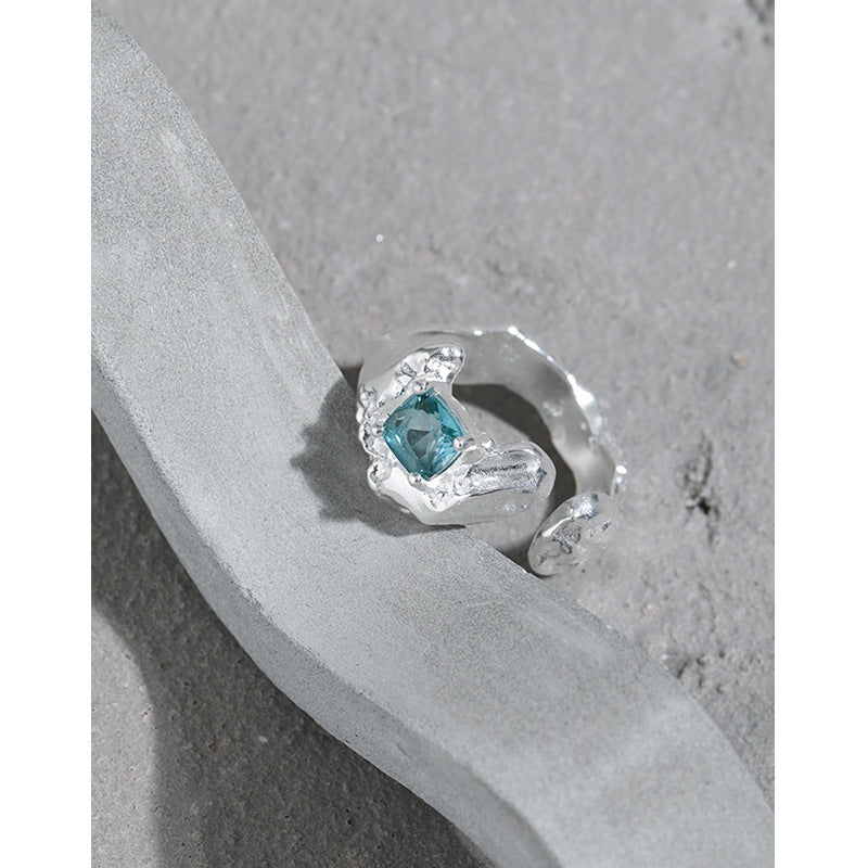 Silver ring with a blue gemstone on a gray surface