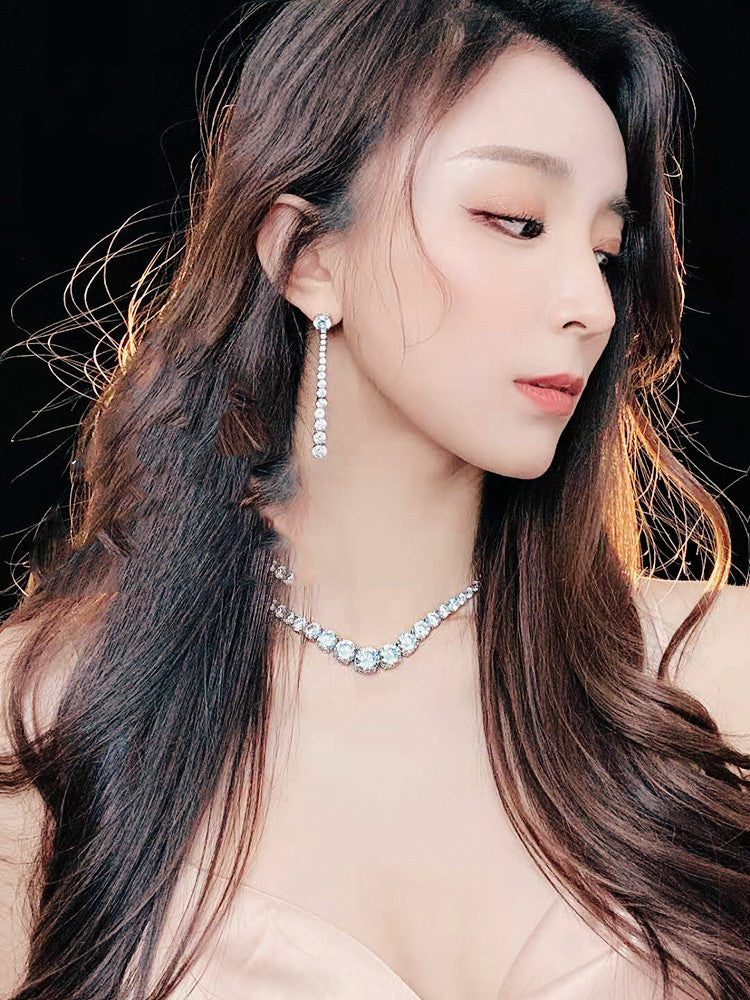 Close-up of a woman wearing earrings and a necklace with a dark background