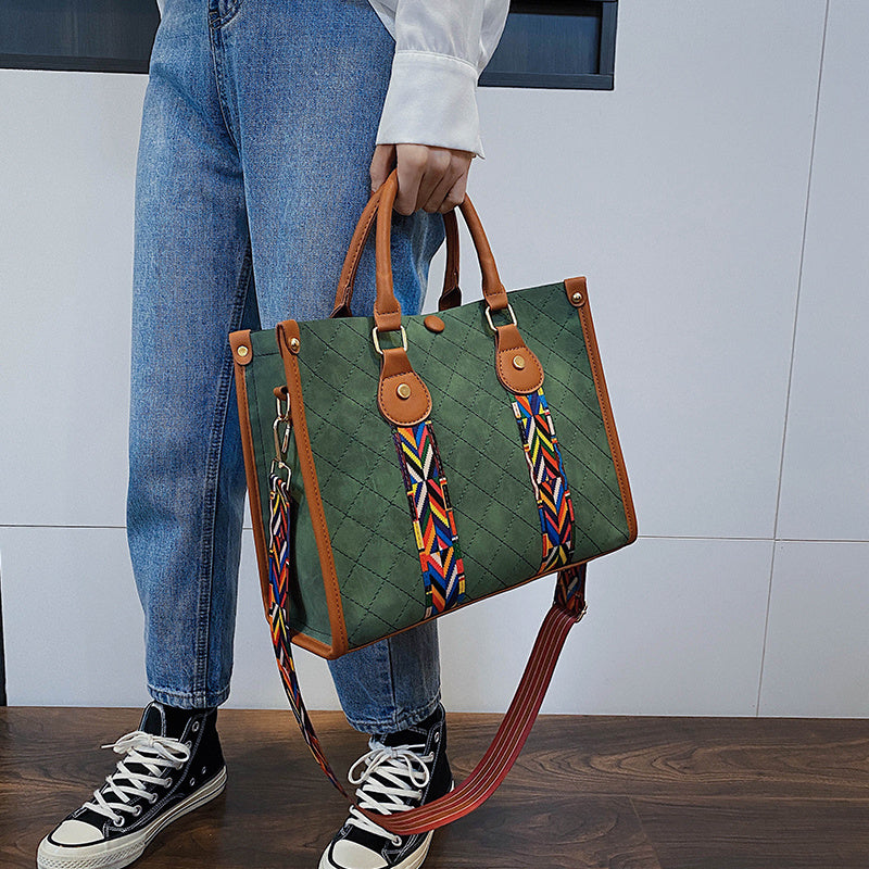 Person holding a green handbag with colorful straps against a white wall.