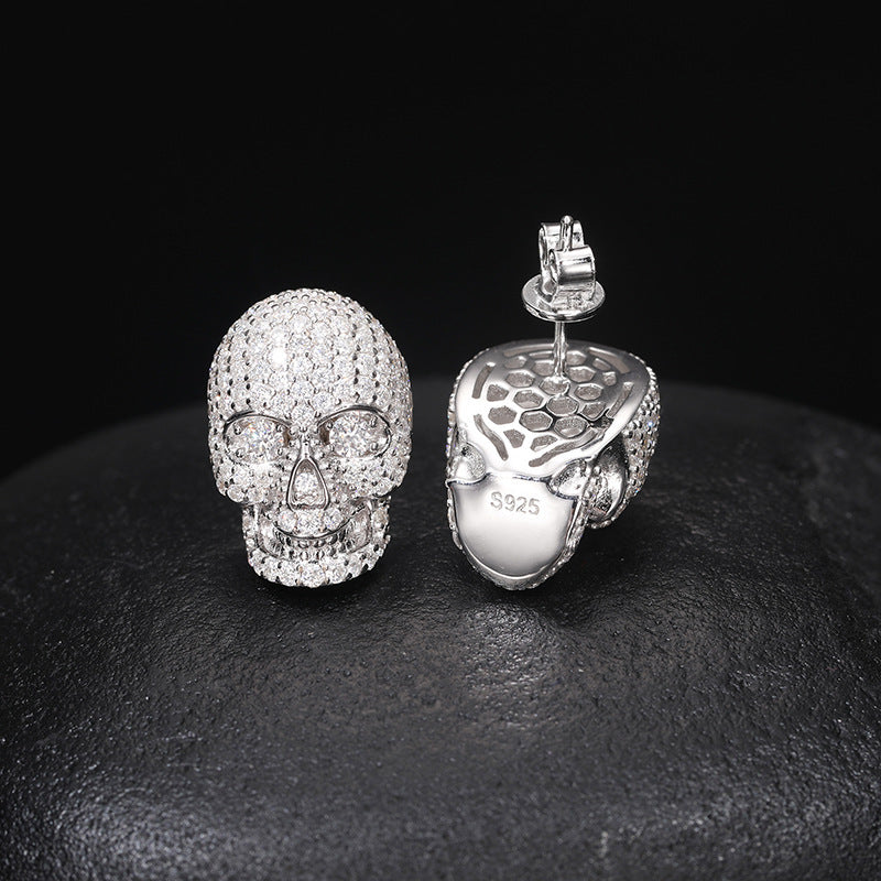 Silver skull-shaped earrings on a dark surface