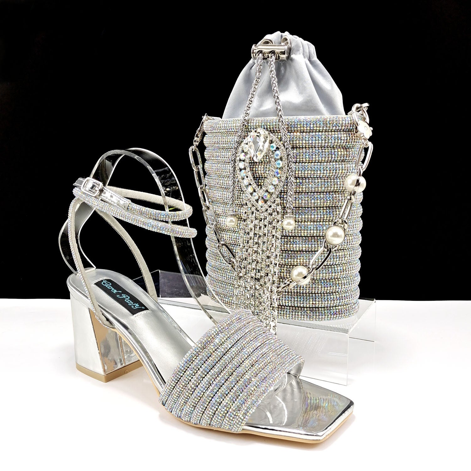 Silver high-heeled shoes and matching handbag with rhinestones on a black background