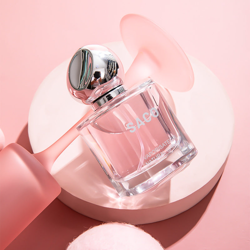 Perfume bottle labeled 'Saco' on a pink background
