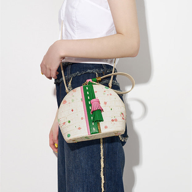 Person holding a small handbag with floral design and colorful accents on a plain background