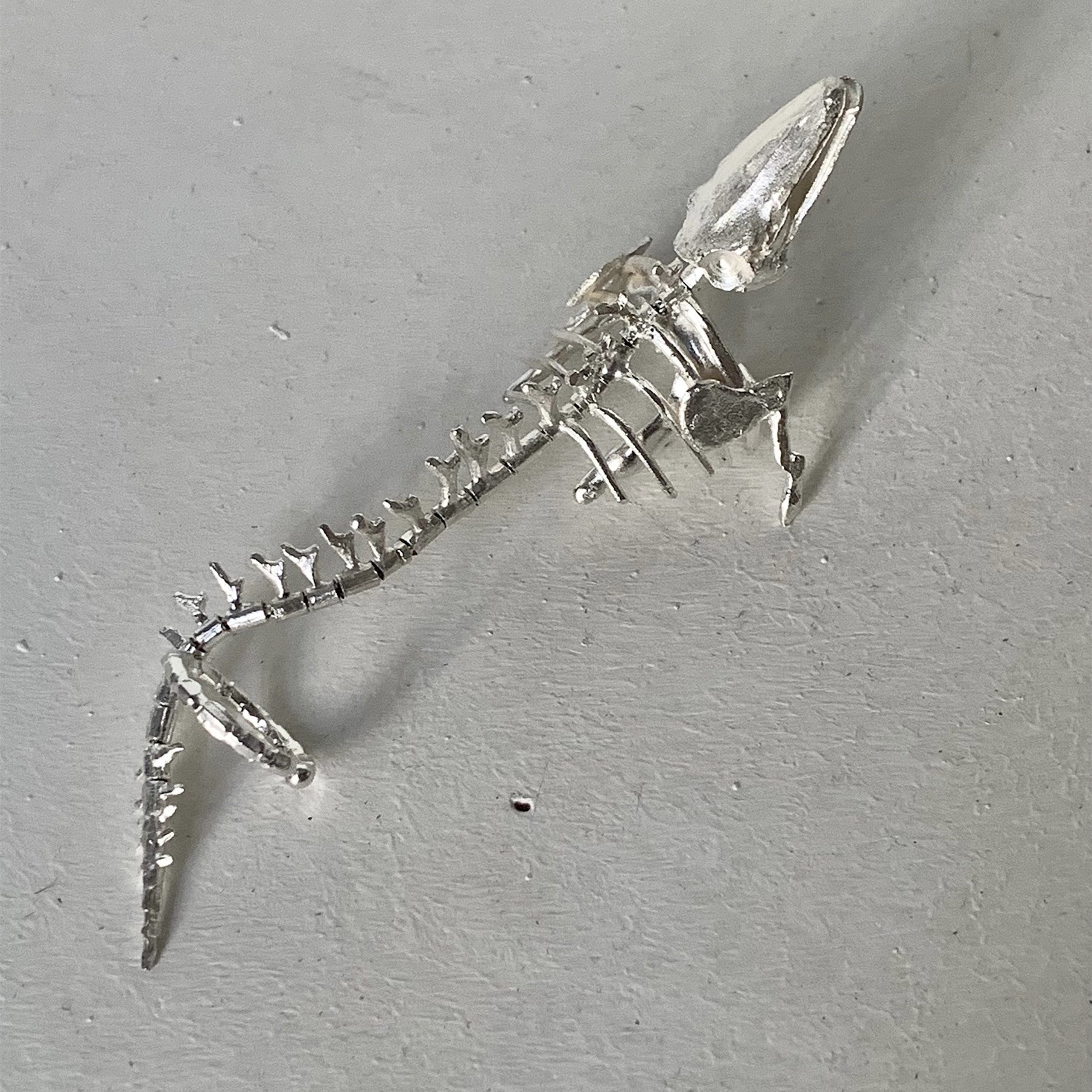 Metallic lizard skeleton model on a gray surface
