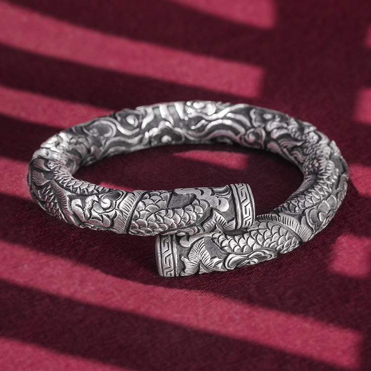 Silver bracelet with intricate patterns on a red background