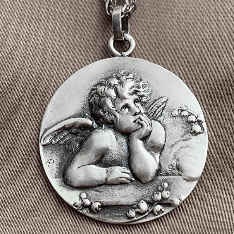 Silver pendant with an angel design on a textured surface