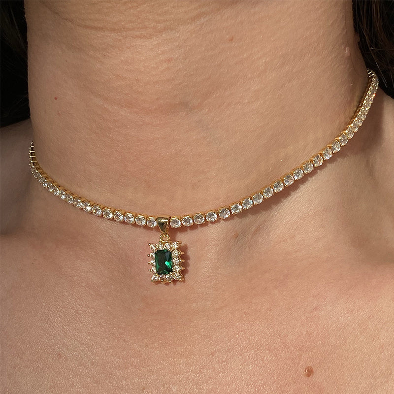 Gold necklace with a green gemstone pendant on a person's neck
