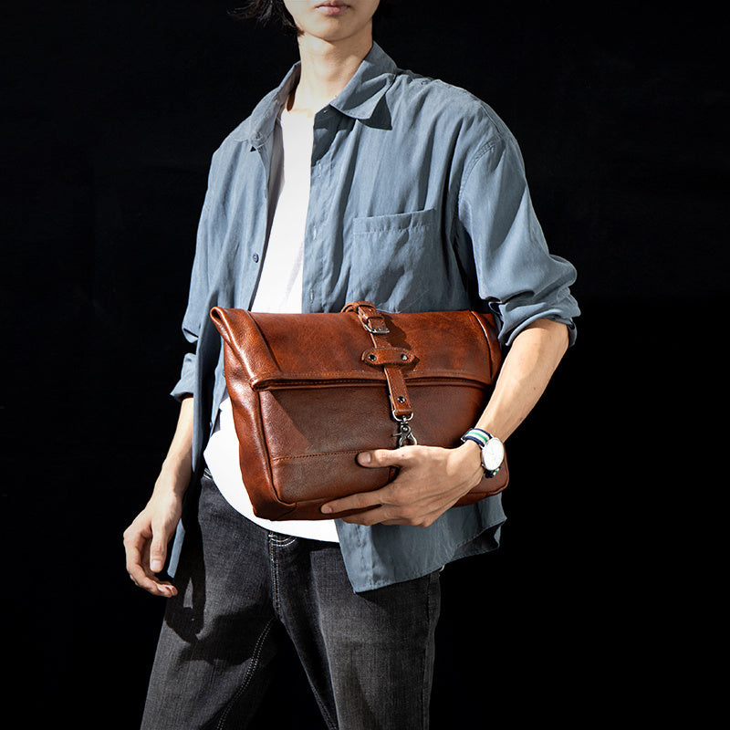 Person holding a brown leather bag against a black background