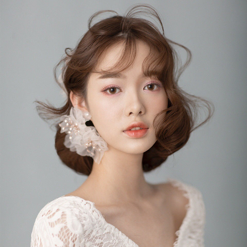 Woman with styled hair and lace top against a gray background