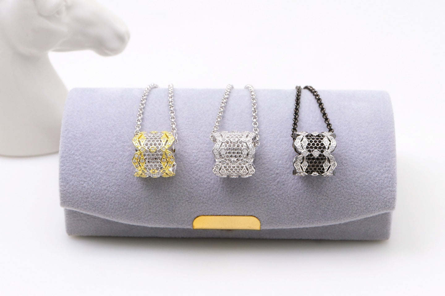 Three necklaces on a gray cushion with a white background