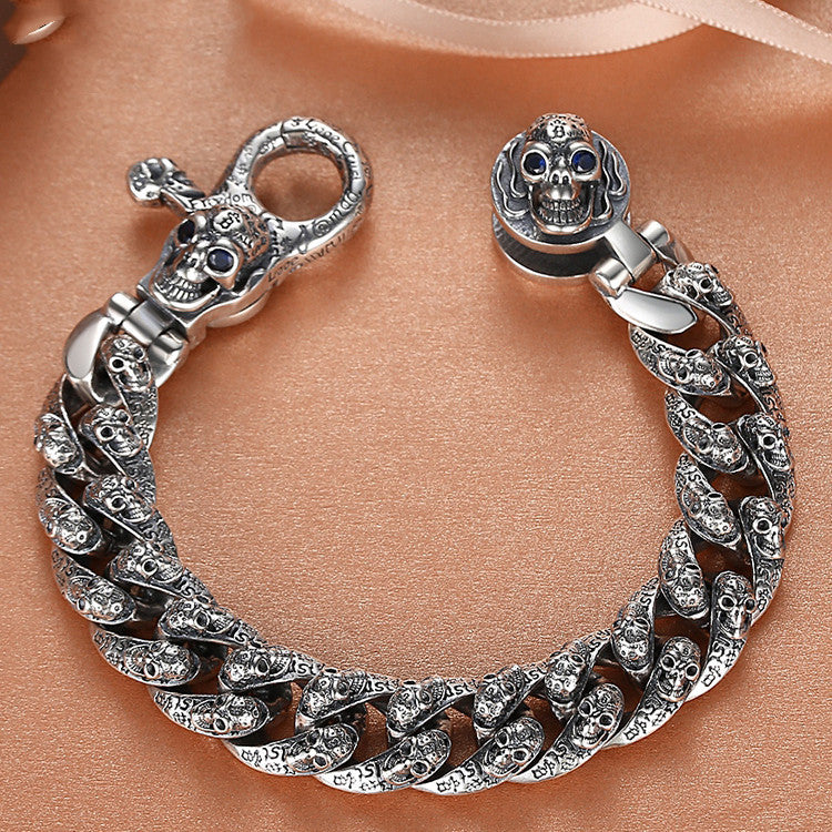 Silver bracelet with skull designs on a peach-colored fabric background