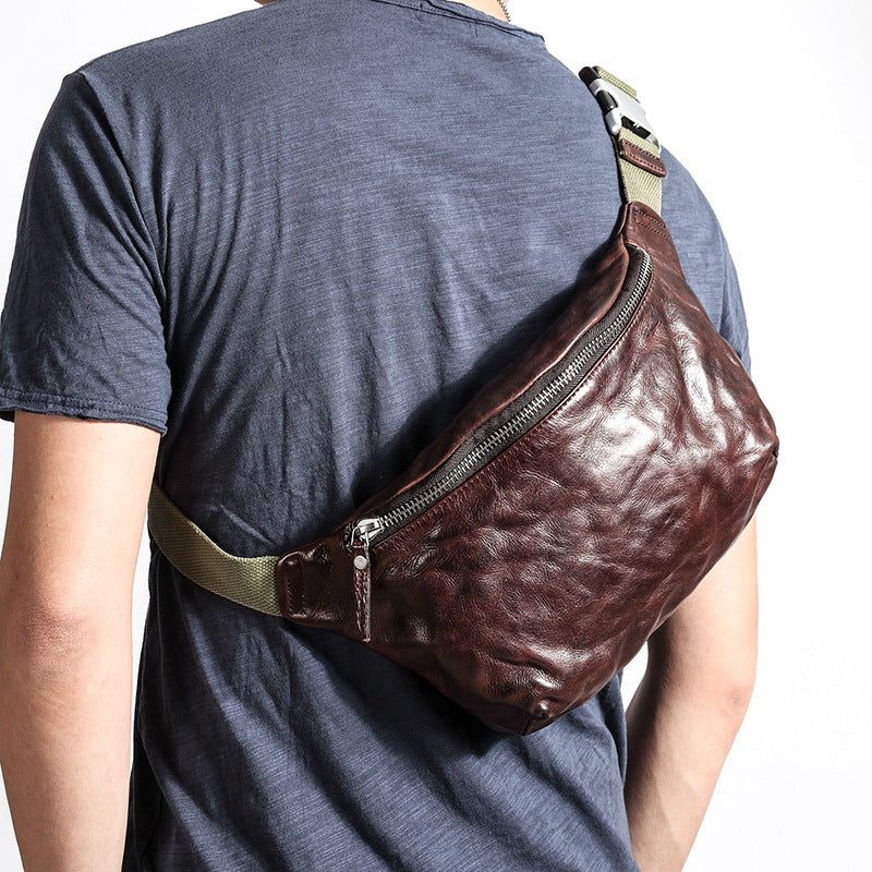 Person wearing a brown leather waist bag on a plain background