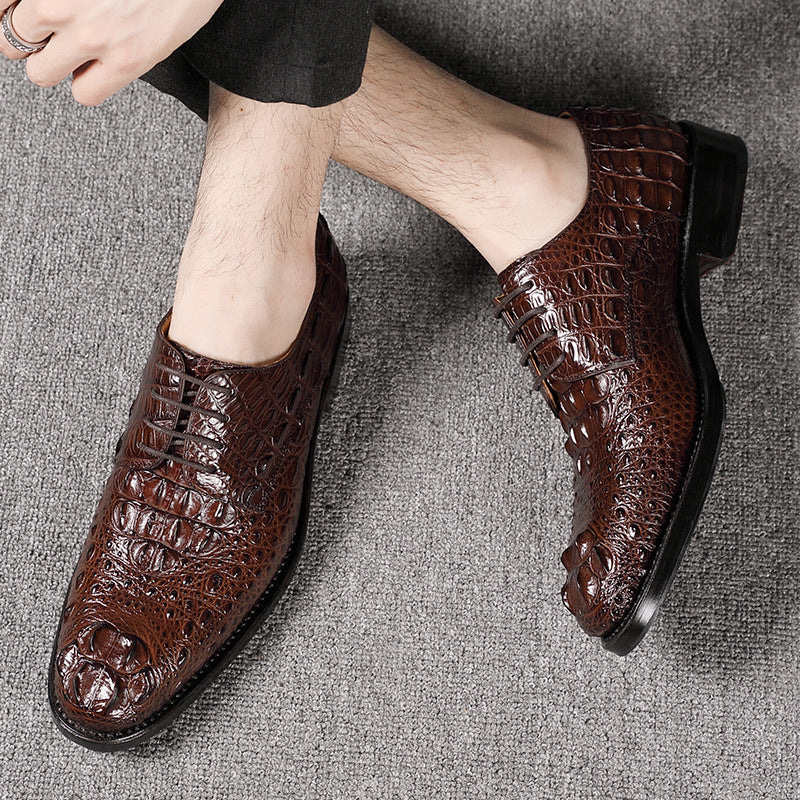 Brown crocodile-patterned shoes on a textured gray surface