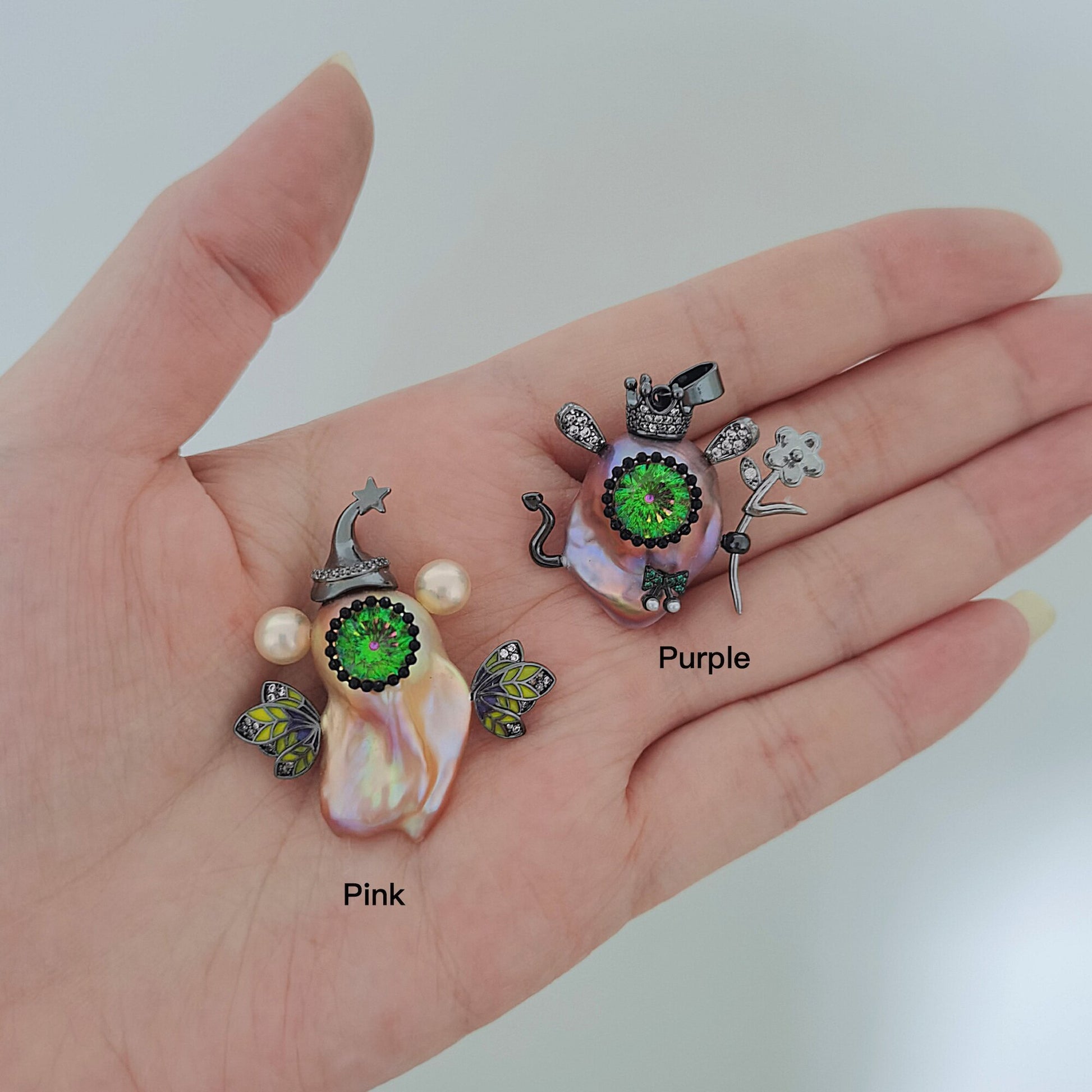 Hand holding three colorful shell pendants labeled 'Pink', 'Purple', and 'Green' on a white background.