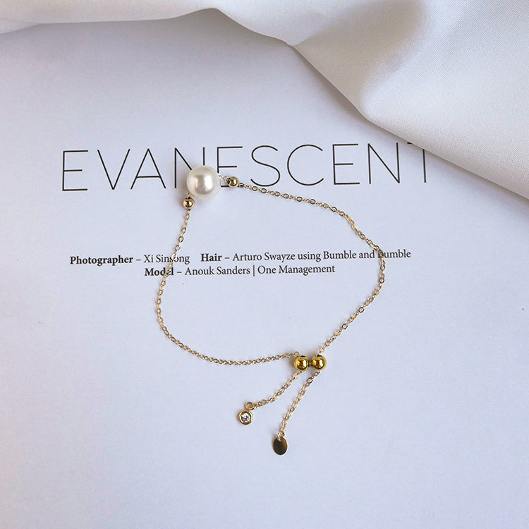 Gold bracelet with pearls on a magazine titled 'Evanescence'.