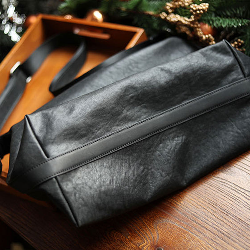 Black leather bag on a wooden surface with a blurred background