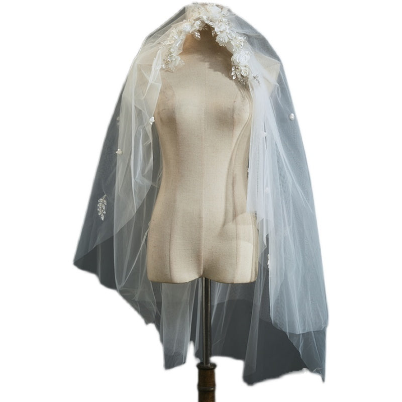 White wedding veil with lace details on a mannequin against a white background