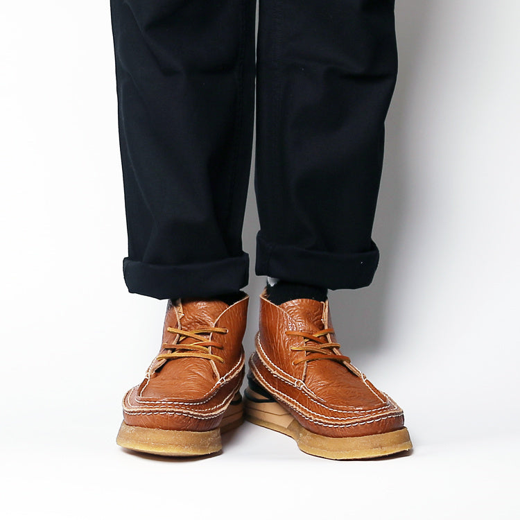 Brown leather boots worn with black pants on a white background