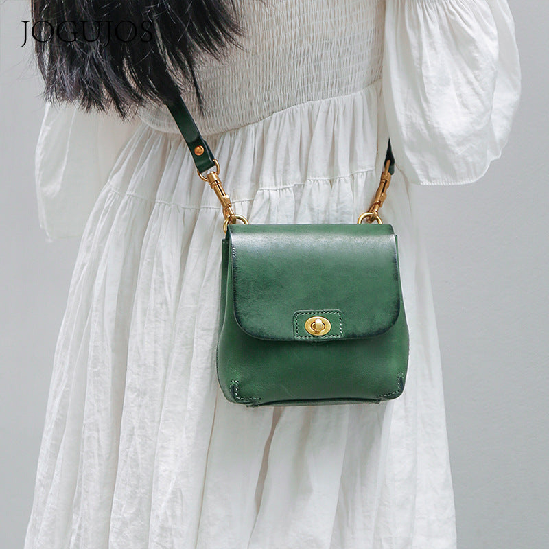 Green handbag worn by a person in a white dress against a plain background