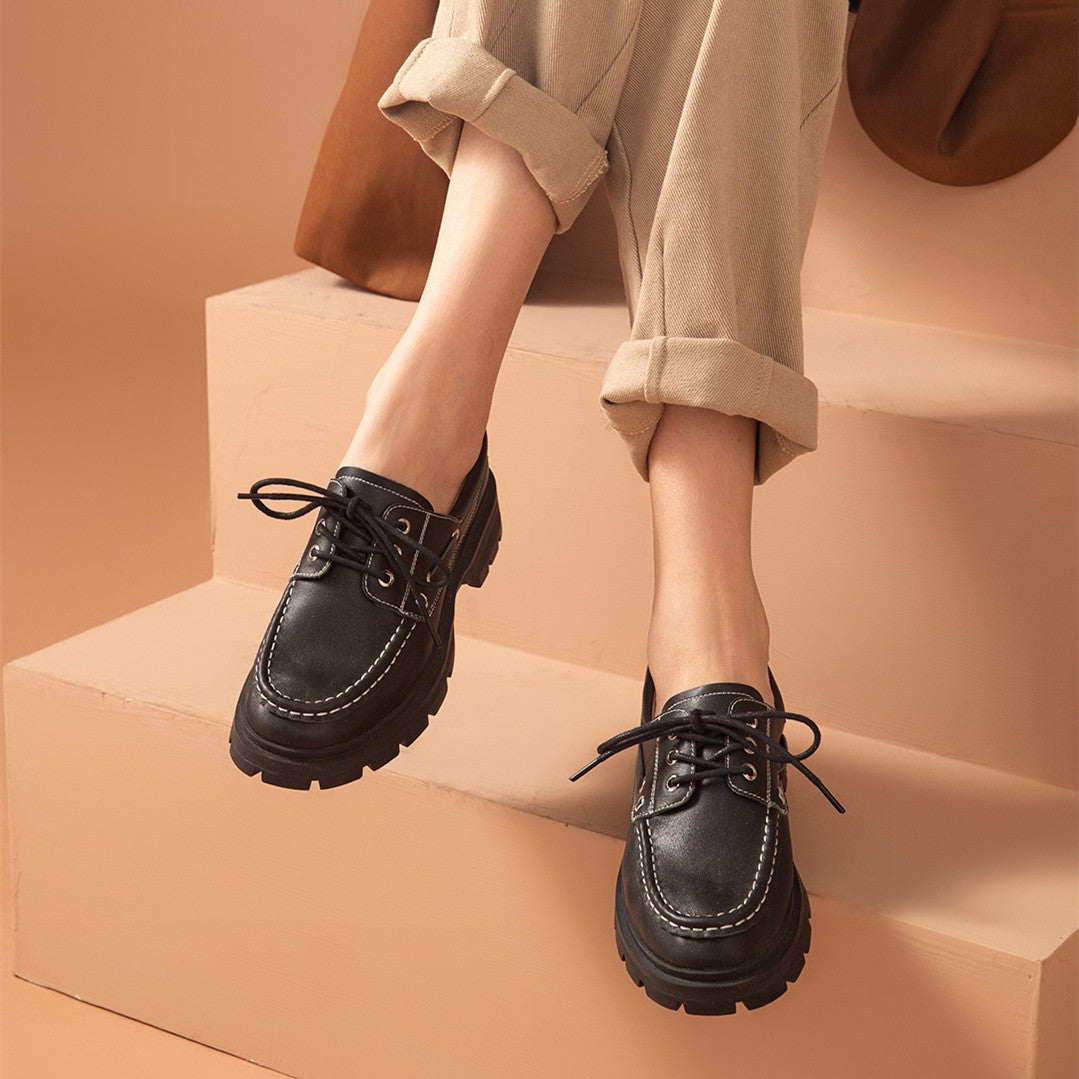 Person wearing black leather shoes on a beige background