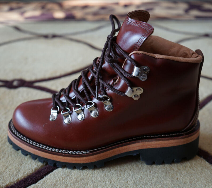 Brown leather boot with laces on a patterned carpet