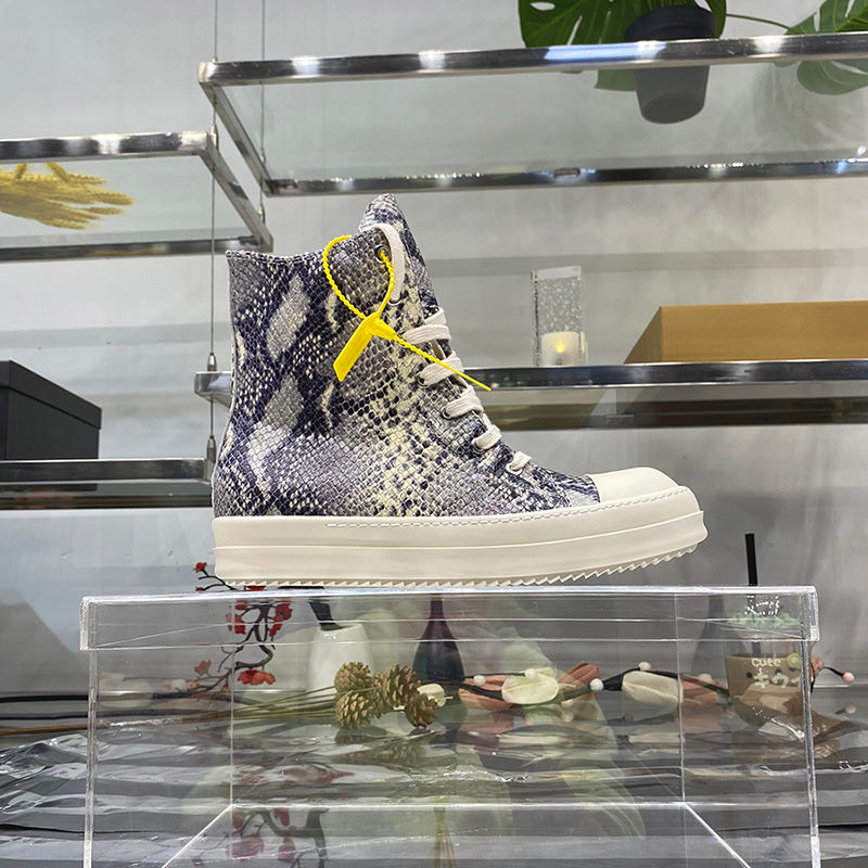 High-top sneaker with snake pattern and yellow accents on a clear stand.
