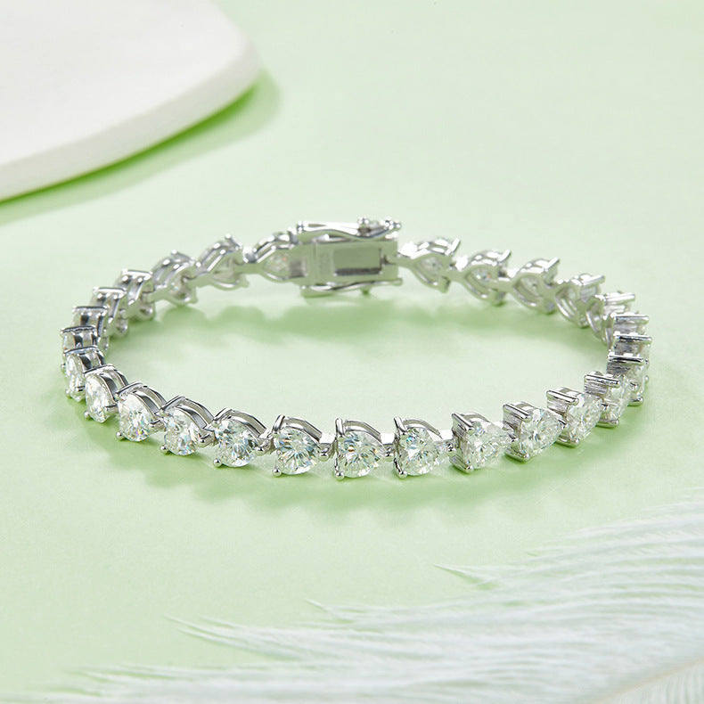 Silver bracelet with clear gemstones on a light green surface