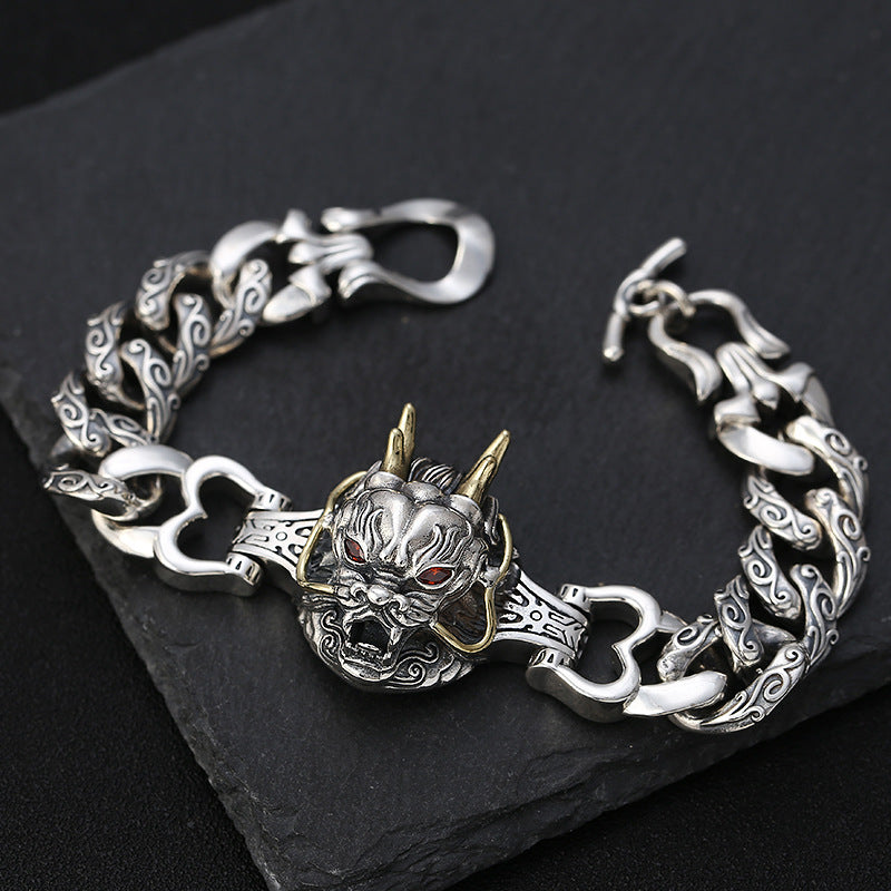 Silver bracelet with dragon head design on a dark surface