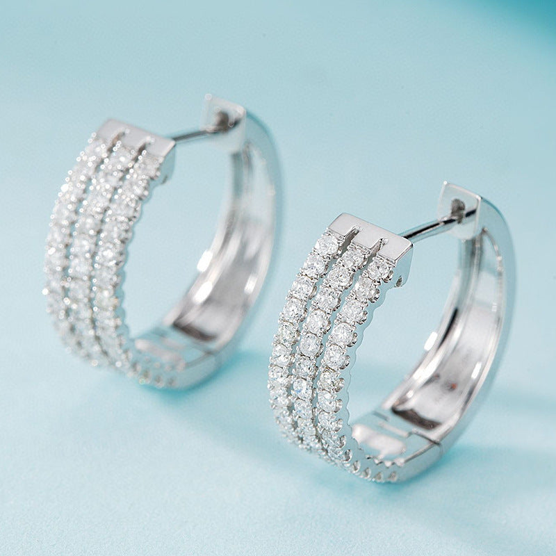 Silver hoop earrings with clear stones on a light blue background