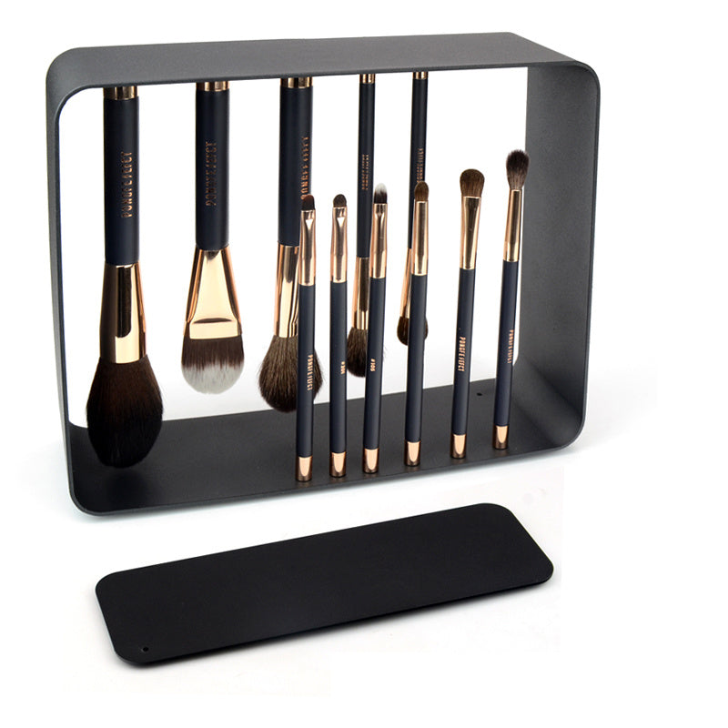 Set of makeup brushes in a black holder on a white background