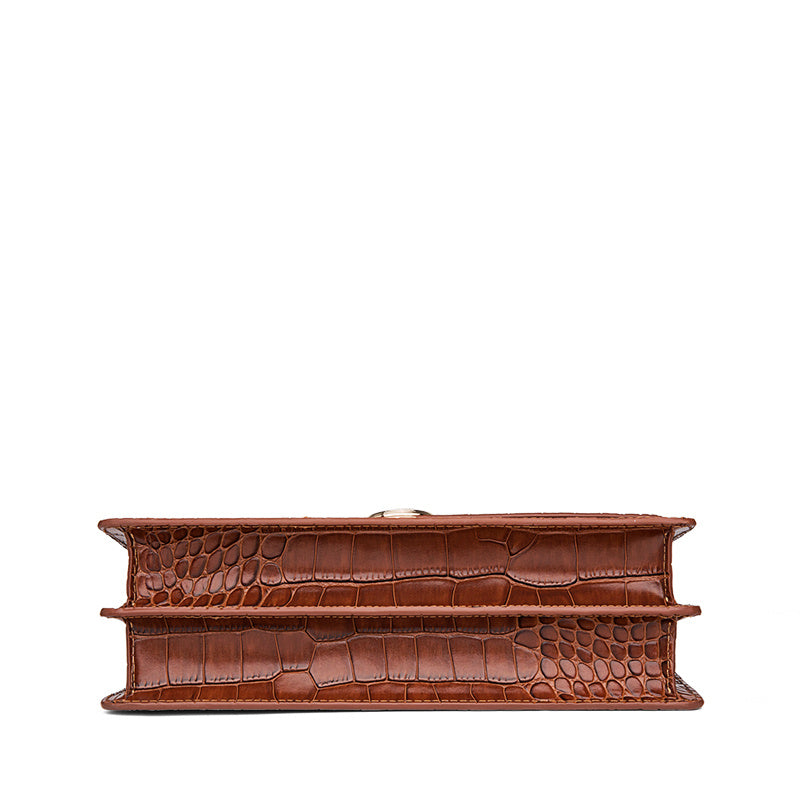 Brown crocodile-patterned clutch bag on a white background