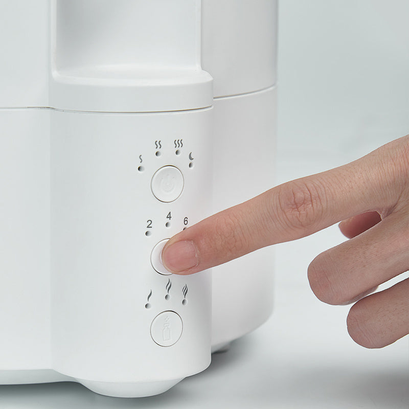 Hand pressing a button on a white electronic device with control panel