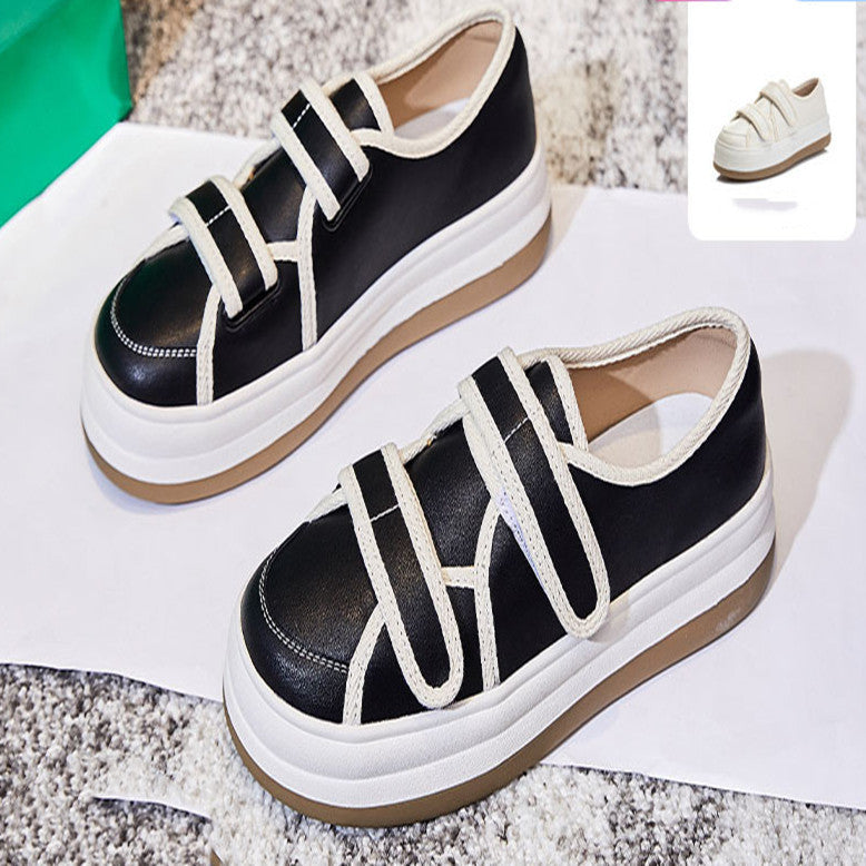 Black and white sneakers with a platform sole on a textured surface.
