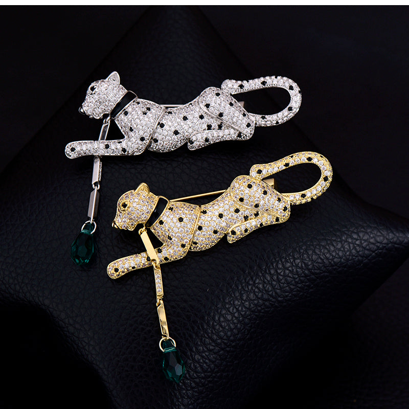 Two cat-shaped brooches, one gold and one silver, on a dark textured surface.