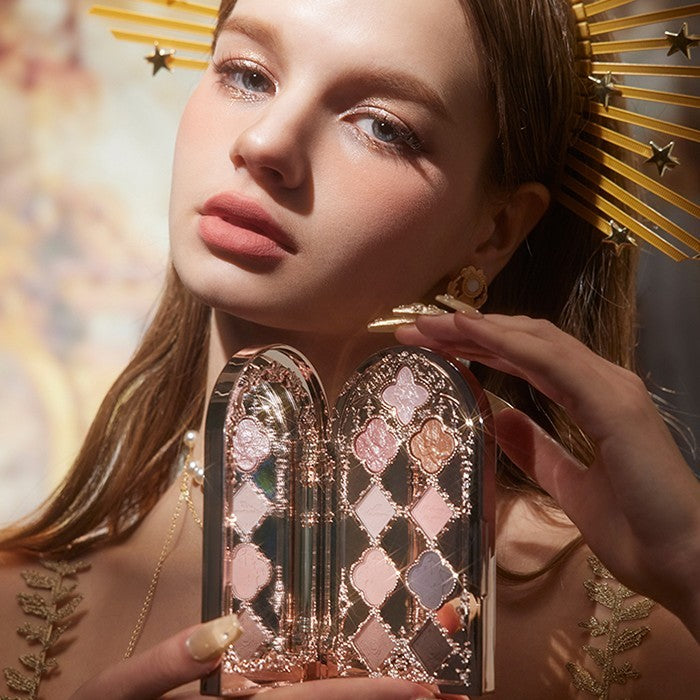 Woman holding a decorative makeup palette with a gold and pink design.