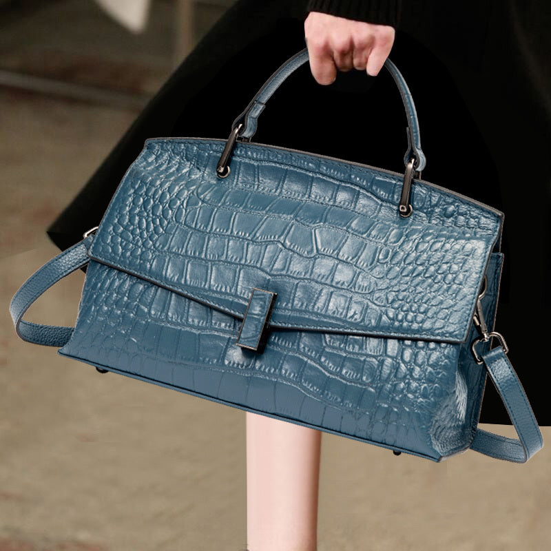Blue textured handbag held by a person with a blurred background