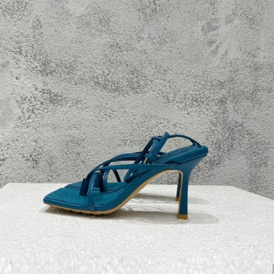 Blue high-heeled sandal on a textured surface with a gray background